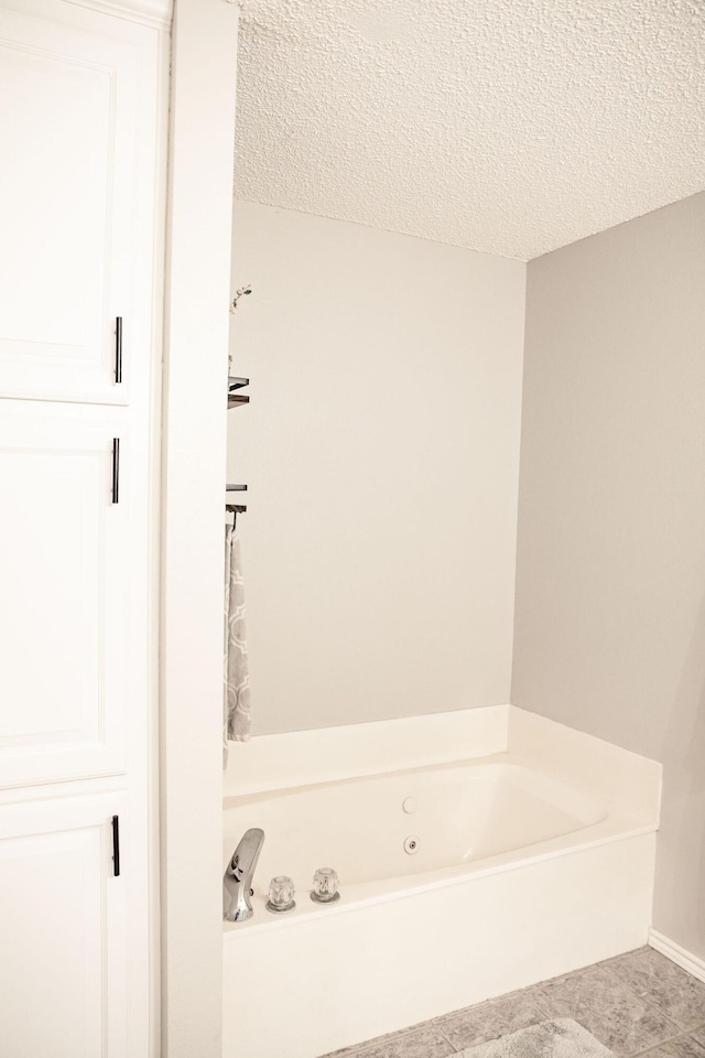 full bathroom with a tub with jets, tile patterned flooring, and a textured ceiling