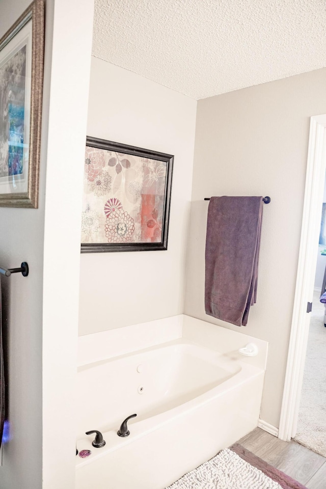 bathroom featuring a whirlpool tub, wood finished floors, and a textured ceiling