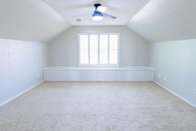 additional living space featuring carpet flooring, a textured ceiling, visible vents, ceiling fan, and lofted ceiling