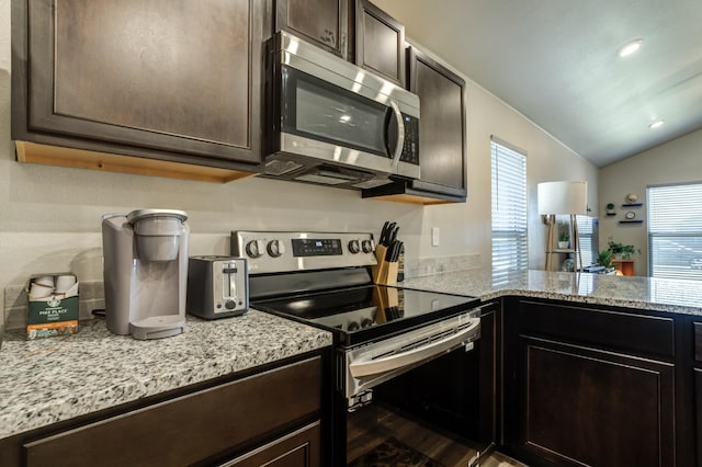 kitchen featuring vaulted ceiling, dark wood-type flooring, light stone counters, stainless steel appliances, and dark brown cabinets