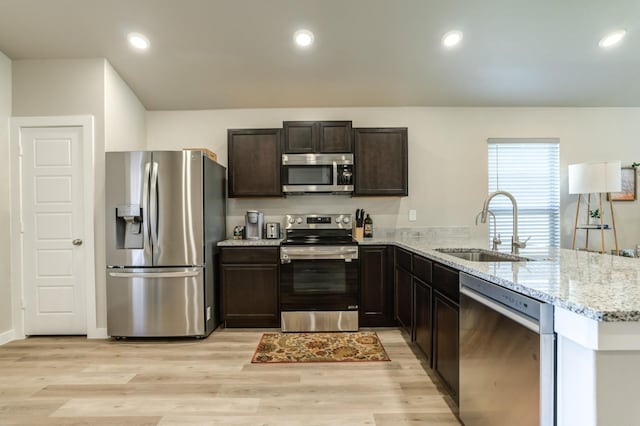 kitchen with sink, light wood-type flooring, kitchen peninsula, and appliances with stainless steel finishes