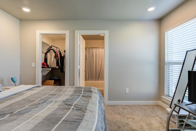 bedroom featuring a walk in closet, connected bathroom, and carpet flooring