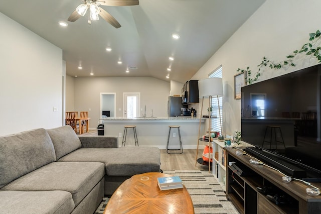 living room with lofted ceiling, sink, ceiling fan, and light wood-type flooring