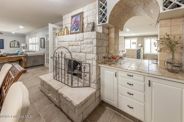 3417 56th St, Lubbock, TX 79413 - kitchen with tile countertops, ornamental molding, open floor plan, healthy amount of natural light, and white cabinets