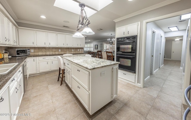 3417 56th St, Lubbock, TX 79413 - kitchen featuring stainless steel appliances, a skylight, crown molding, a kitchen island, and white cabinetry
