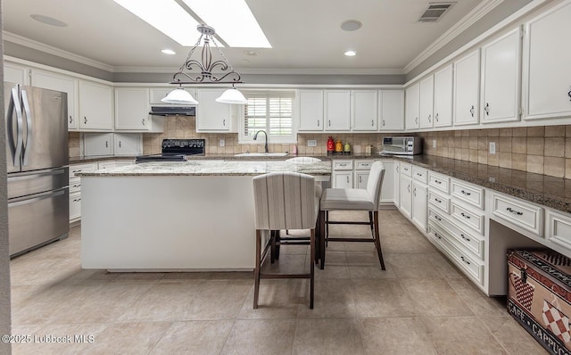 3417 56th St, Lubbock, TX 79413 - kitchen featuring freestanding refrigerator, black range with electric stovetop, under cabinet range hood, a kitchen island, and crown molding