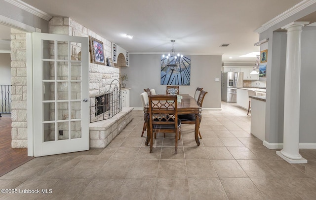 3417 56th St, Lubbock, TX 79413 - dining room with crown molding, a chandelier, ornate columns, a stone fireplace, and light tile patterned floors