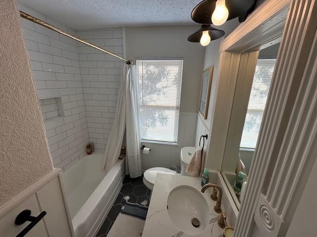 full bathroom featuring shower / tub combo, plenty of natural light, sink, and a textured ceiling