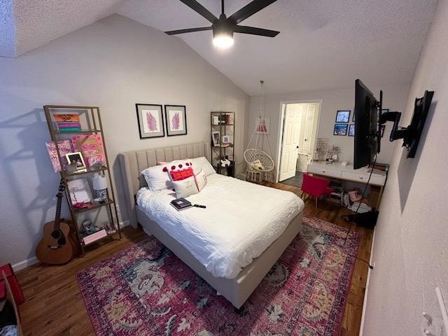 bedroom featuring ceiling fan, dark hardwood / wood-style floors, vaulted ceiling, and a textured ceiling