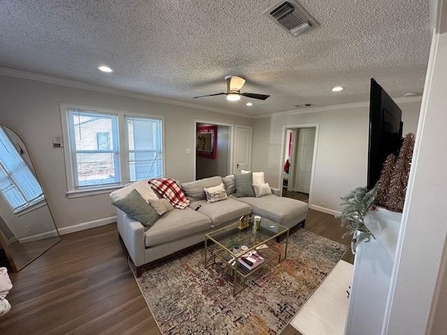 living room featuring crown molding, ceiling fan, dark hardwood / wood-style floors, and a textured ceiling