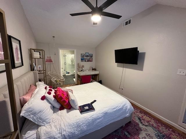 bedroom with ceiling fan, ensuite bathroom, and vaulted ceiling