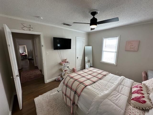 bedroom with crown molding, ceiling fan, dark hardwood / wood-style flooring, and a textured ceiling