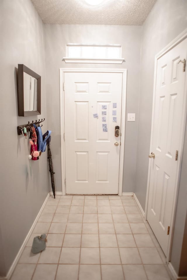 doorway featuring light tile patterned flooring and a textured ceiling