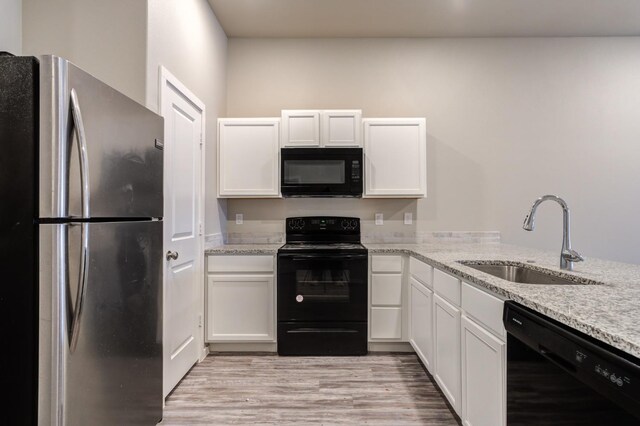 kitchen with light stone countertops, white cabinetry, sink, and black appliances