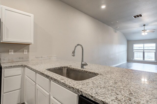 kitchen featuring sink, vaulted ceiling, ceiling fan, light stone countertops, and white cabinetry