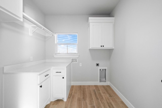 laundry area featuring cabinets, electric dryer hookup, and light hardwood / wood-style flooring