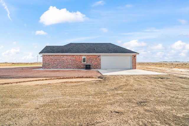 exterior space with cooling unit, a garage, and a lawn