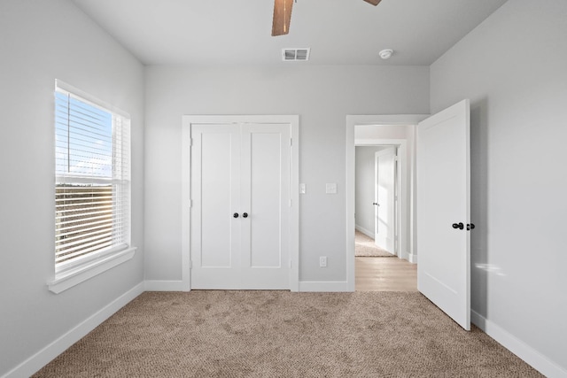 unfurnished bedroom featuring light carpet, a closet, and ceiling fan