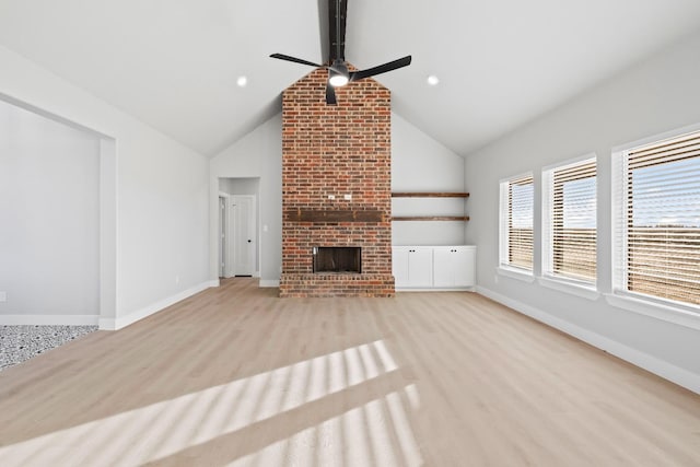 unfurnished living room with ceiling fan, lofted ceiling, a fireplace, and light hardwood / wood-style flooring