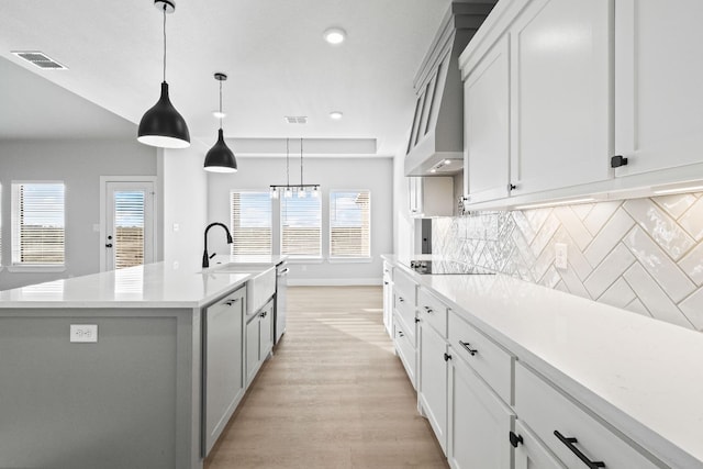 kitchen featuring a kitchen island with sink, hanging light fixtures, white cabinetry, and black electric cooktop