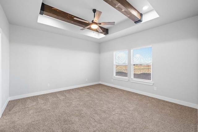 empty room with beamed ceiling, a raised ceiling, ceiling fan, and carpet