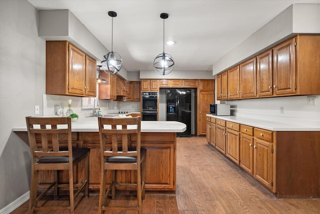 3808 27th St, Lubbock, TX 79410 - kitchen featuring black appliances, a peninsula, brown cabinetry, and light countertops