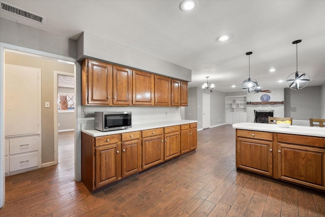 3808 27th St, Lubbock, TX 79410 - kitchen featuring stainless steel microwave, brown cabinetry, light countertops, dark wood-style flooring, and recessed lighting