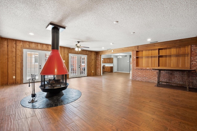 3808 27th St, Lubbock, TX 79410 - unfurnished living room featuring a wood stove, a textured ceiling, a ceiling fan, wood finished floors, and french doors