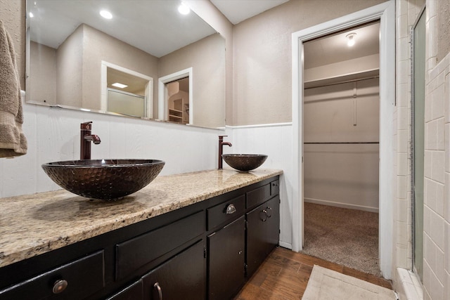 3808 27th St, Lubbock, TX 79410 - full bathroom with wood finished floors, a spacious closet, double vanity, a stall shower, and wainscoting