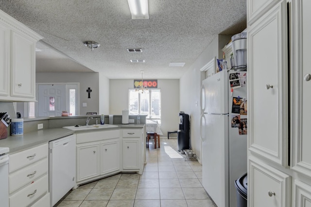 kitchen with sink, white cabinets, light tile patterned floors, kitchen peninsula, and white appliances