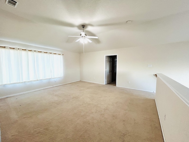 spare room featuring a ceiling fan, visible vents, light carpet, and baseboards