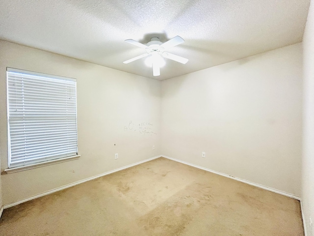 carpeted empty room featuring ceiling fan, a textured ceiling, and baseboards