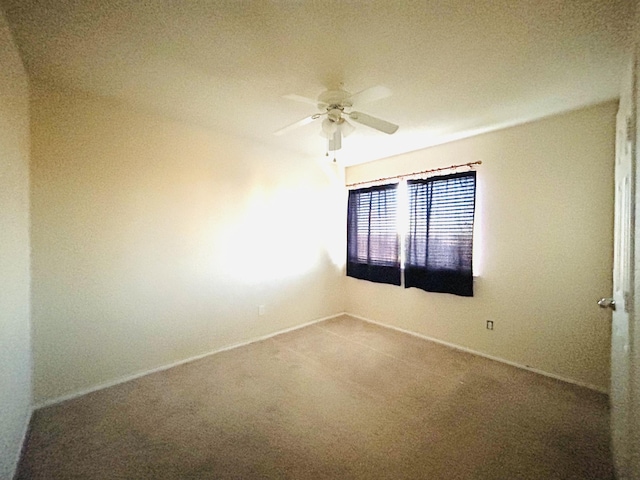 carpeted spare room with ceiling fan and baseboards