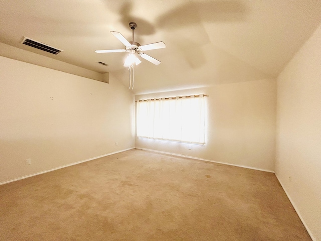 empty room featuring light carpet, lofted ceiling, visible vents, and a ceiling fan