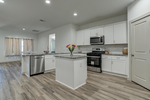 6904 56th St, Lubbock, TX 79407 - kitchen featuring appliances with stainless steel finishes, a peninsula, light wood-style flooring, white cabinetry, and recessed lighting