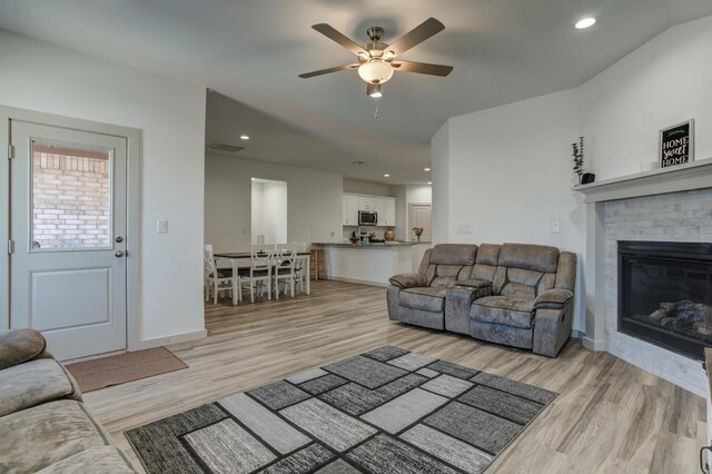 6904 56th St, Lubbock, TX 79407 - living room with light wood-style floors, ceiling fan, a brick fireplace, baseboards, and recessed lighting