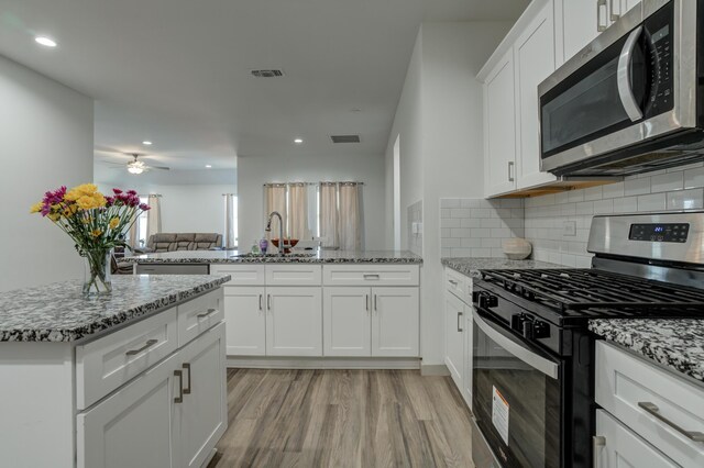 6904 56th St, Lubbock, TX 79407 - kitchen with appliances with stainless steel finishes, a sink, light wood finished floors, backsplash, and light stone countertops