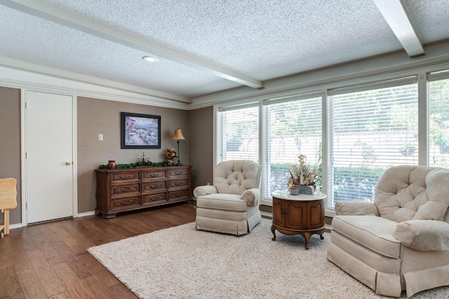 sitting room with beam ceiling, a wealth of natural light, a textured ceiling, and hardwood / wood-style flooring