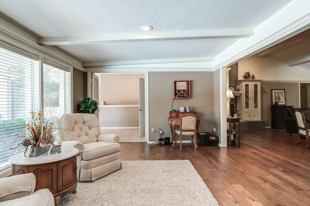 living area with hardwood / wood-style flooring, a textured ceiling, and beam ceiling