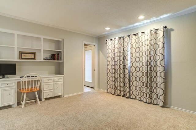 office featuring crown molding, built in desk, and light carpet