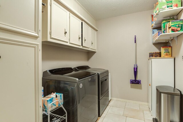 laundry area with washing machine and dryer, cabinets, a textured ceiling, and light tile patterned flooring