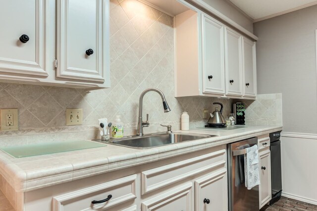 kitchen featuring tasteful backsplash, sink, stainless steel dishwasher, and white cabinets