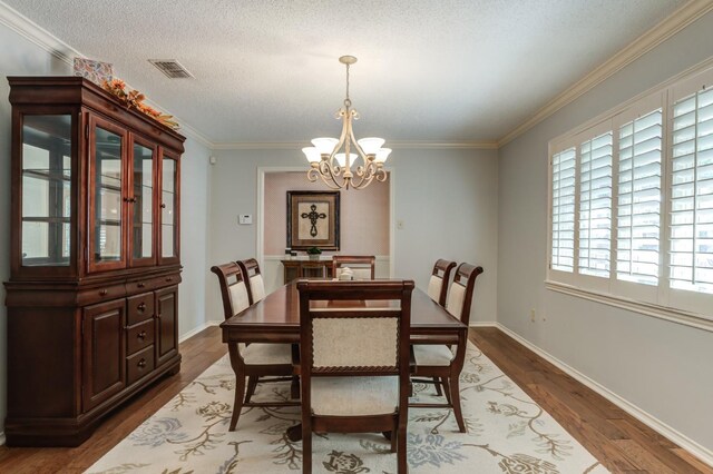 dining area with ornamental molding, dark hardwood / wood-style floors, a textured ceiling, and an inviting chandelier