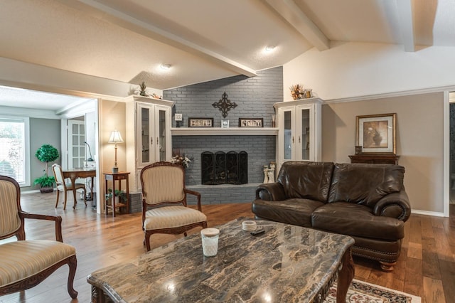 living room featuring a fireplace, lofted ceiling with beams, and hardwood / wood-style floors