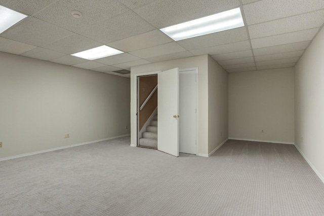 basement with light colored carpet and a paneled ceiling