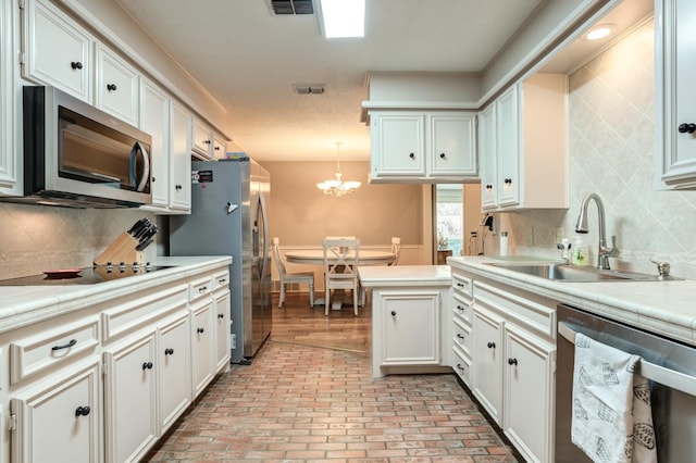 kitchen with sink, tasteful backsplash, decorative light fixtures, stainless steel appliances, and white cabinets