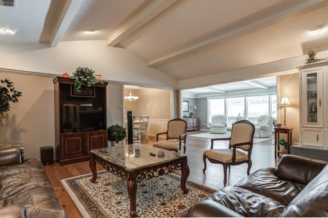 living room with dark wood-type flooring, a chandelier, and vaulted ceiling with beams