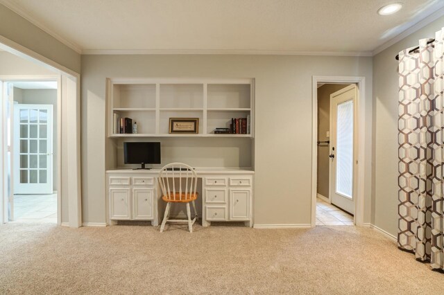 office featuring ornamental molding, built in desk, and light colored carpet