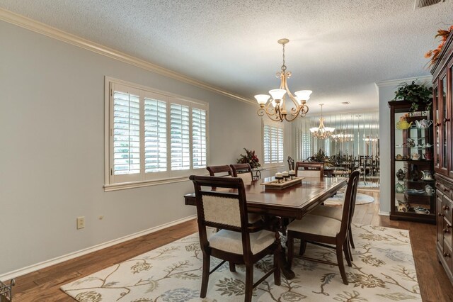 dining room featuring hardwood / wood-style flooring, ornamental molding, a notable chandelier, and a textured ceiling