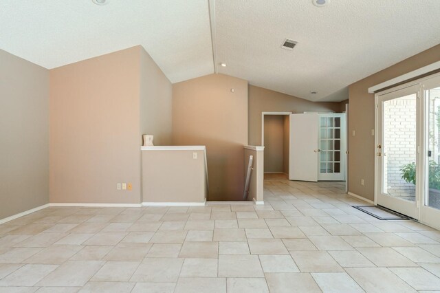 tiled empty room with lofted ceiling and a textured ceiling